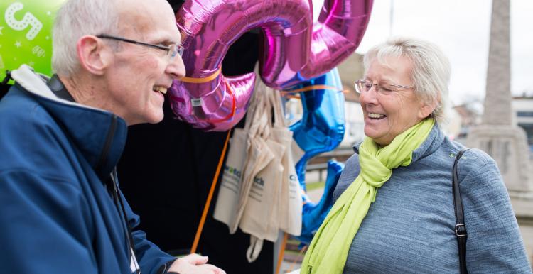 Elderly man and woman talking together at a Healthwatch event