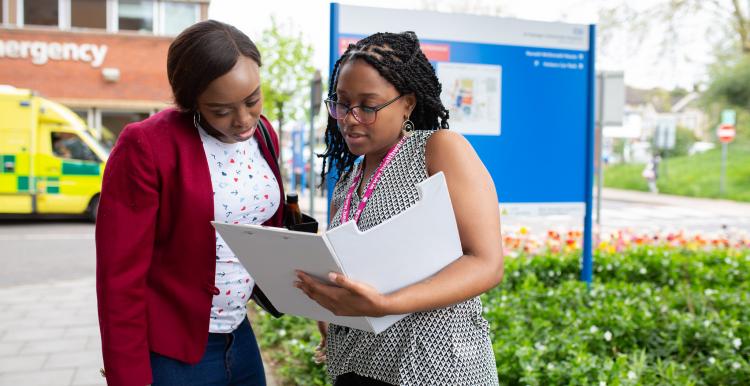 Women looking at file in front of hospital sign